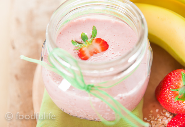 Strawberry and banana smoothy in a glass jar on green napkin, on a wood board, frullato di fragole e banana 