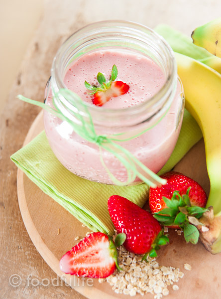 Strawberry and banana smoothy in a glass jar on green napkin, on a wood board, frullato di fragole e banana 